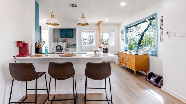 Una cocina moderna con una isla central, taburetes de bar, un mueble de madera y un amplio ventanal con vistas.