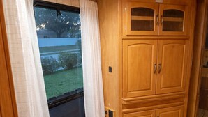 Een kamer met een groot raam, houten kastjes en een vloerbedekking.