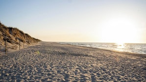 Een strand met duinen en een heldere lucht.