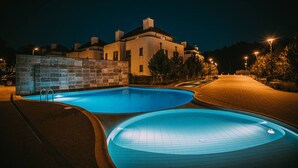 Un espace piscine avec un mur en pierre et un bâtiment en arrière-plan.