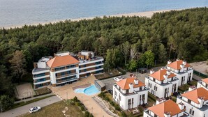 Un hôtel à plusieurs étages doté d’une piscine, entouré d’une forêt et bordé d’une plage.