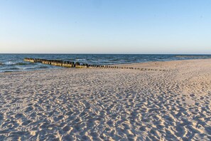 A sandy beach with a wooden jetty extending into the water. - Oaza Spokoju Widok na Las Design Shellter (Trzebiatow)