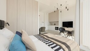 A modern bedroom with a bed, a TV, a desk, and a kitchenette. - Widok na Morze Przy Pla y Taras Shellter (Trzebiatow)