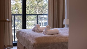 A hotel room with a bed, a window with curtains, and a view of trees outside. - Duna Taras Shellter Rogowo Morze (Trzebiatow)