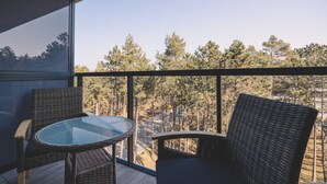 A balcony with wicker furniture and a glass table, overlooking a forest. - Duna Taras Shellter Rogowo Morze (Trzebiatow)