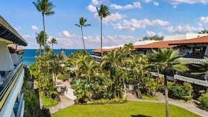 A resort with a pool area, palm trees, and a view of the ocean. - Casa De Emdeko 303 | Ocean View | Central AC (Kailua Kona)