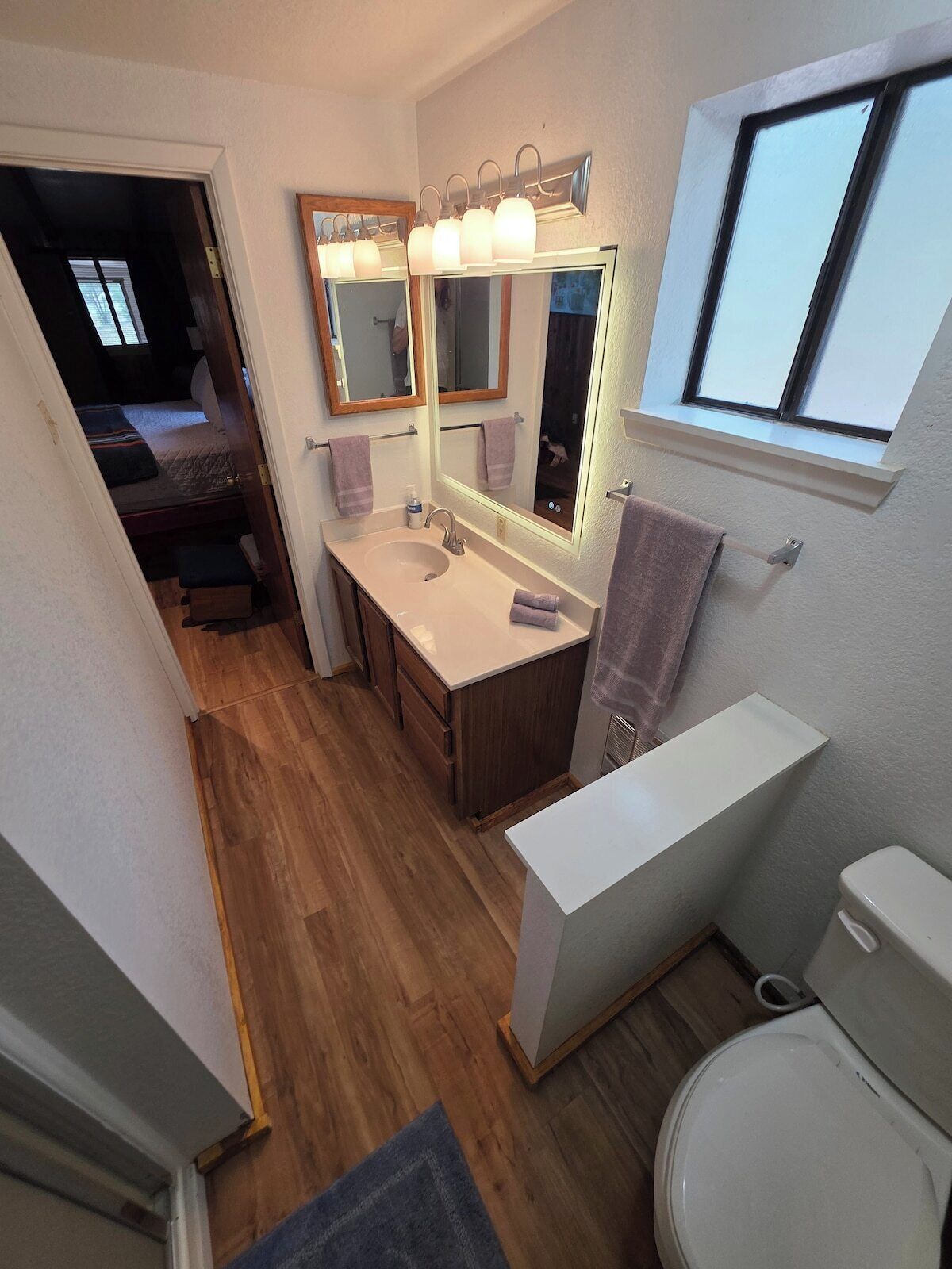 Bathroom sink with fresh towels and lighted mirror.