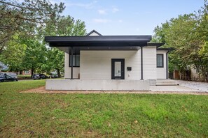 A modern single-story house with a flat roof, a front porch, and a well-maintained lawn. - Large Clean & Modern Basement Apartment Near Aggie (Manhattan)