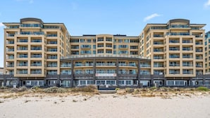 Ein mehrstöckiges Hotel mit einem zentralen Atrium, Balkonen und Blick auf den Strand.
