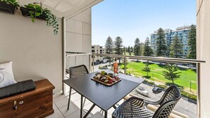 Ein Balkon mit Tisch, gedecktem Esstisch, einer Couch und Blick auf eine Wohngegend.