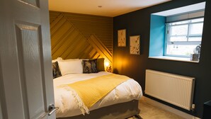 Ein Schlafzimmer mit Bett, Fenster, Heizkörper und Tür.