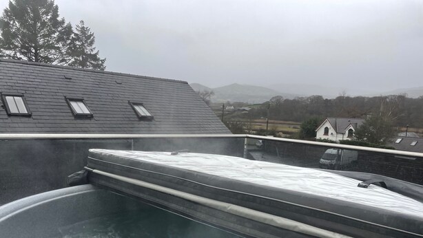 Ein Whirlpool auf einem Dach mit Blick auf Häuser und Bäume im Hintergrund.