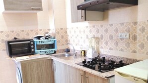 A compact kitchen with a built-in microwave, a toaster, a blender, and a gas stove.