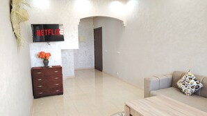 A modern living room with a flat-screen TV, a wooden cabinet, a sofa, and a dining table.