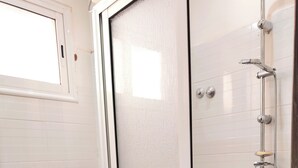 A bathroom with a toilet, a shower enclosure, and tiled walls.