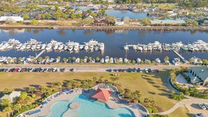 A marina with boats docked, a swimming pool with sun loungers, and a view of the city skyline. - Eagles Townhouse at Barefoot - Golf, Beach, Pools - Your Coastal Golf Escape! (North Myrtle Beach)