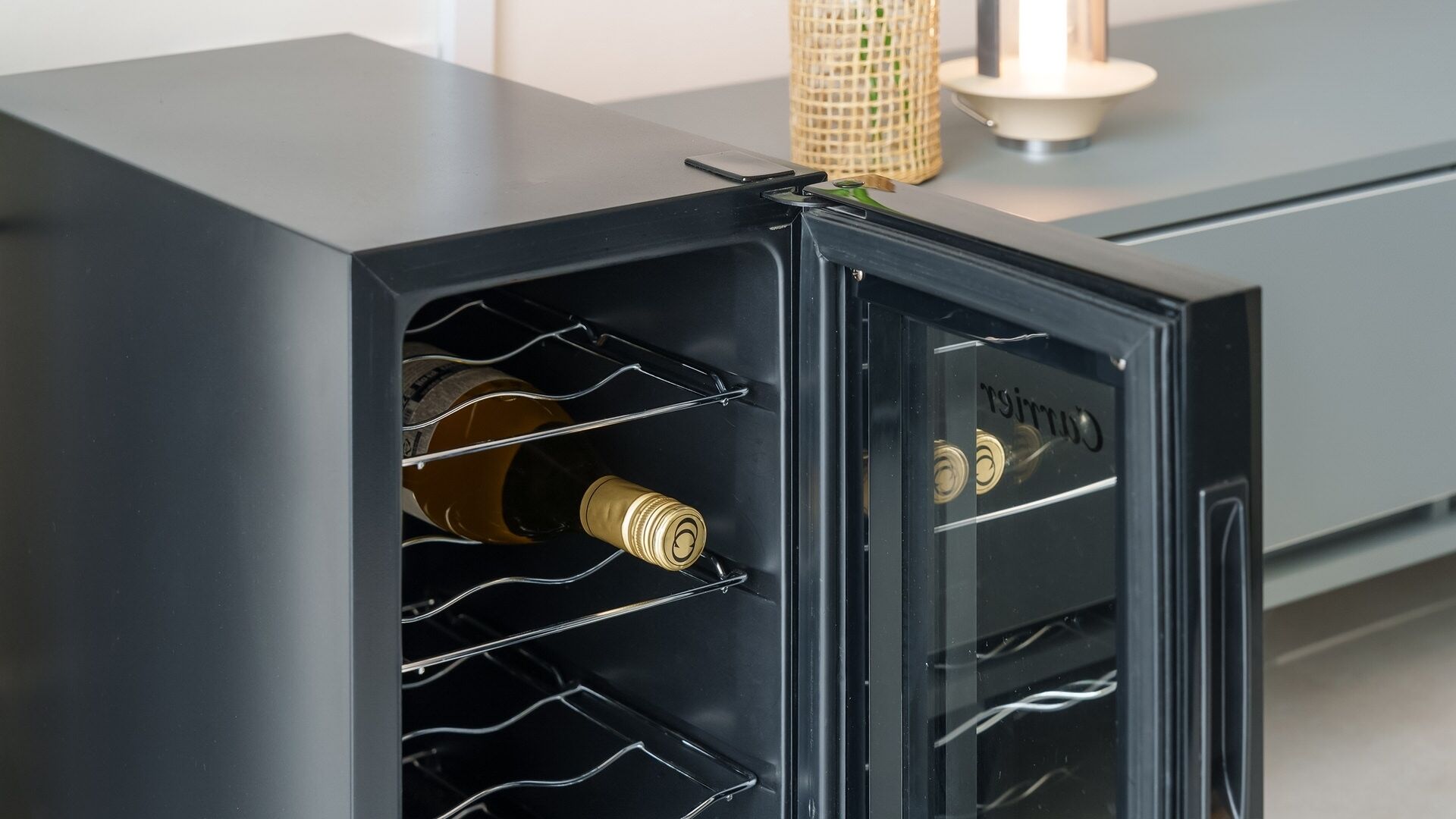 A black safe with a wine rack, a bottle, and a key.