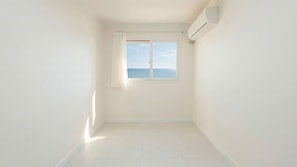 Una habitación con un ventanal grande, paredes blancas y piso de baldosas.