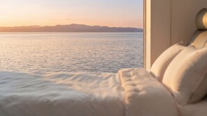 A bed with a view of a calm sea and distant mountains. - Daebudo Sunbell Ocean View Pension (Ansan)