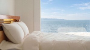 Un lit avec une tête de lit, une fenêtre donnant sur la mer et une tête de lit en bois.
