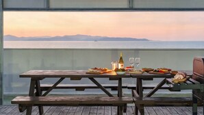 A wooden table with food and drinks, overlooking a body of water and mountains. - Daebudo Sunbell Ocean View Pension (Ansan)