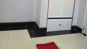 A room with a wardrobe, a red rug, and a tiled floor. - Nha nghi Nguyen Bao  - Tran De Con Dao (Can Tho)