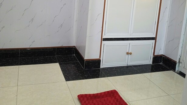 A room with a wardrobe, a red rug, and a tiled floor. - Nha nghi Nguyen Bao  - Tran De Con Dao (Can Tho)