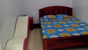 A bedroom with a bed, a bedside table, a chair, and an air conditioning unit. - Nha nghi Nguyen Bao  - Tran De Con Dao (Can Tho)