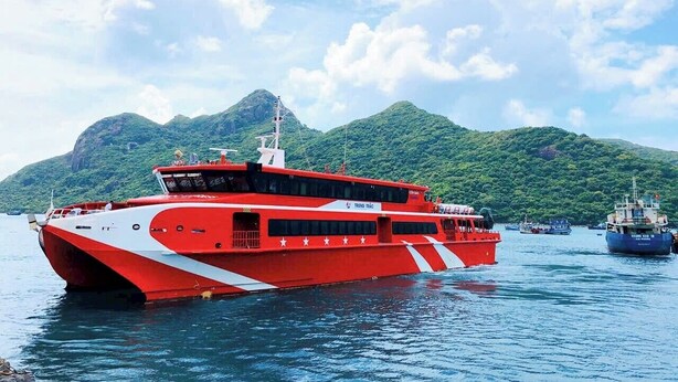 A red and white boat with 'TRUNG TRANG' written on it, docked in calm waters with mountains in the background. - Nha nghi Nguyen Bao  - Tran De Con Dao (Can Tho)