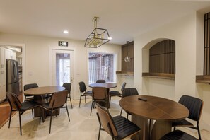 A modern dining area with round tables and chairs, a chandelier, and a view of the outside.