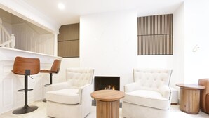 Una sala moderna con dos sillones, una mesa de centro redonda de madera y una chimenea.