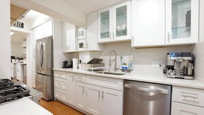 Una cocina moderna con armarios blancos, electrodomésticos de acero inoxidable y lavavajillas.