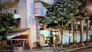 A hotel with multiple balconies, outdoor seating, and bicycles parked outside. - Spacious 2-BR/2-bath suite with full kitchen & living room, minutes from beach (Honolulu)