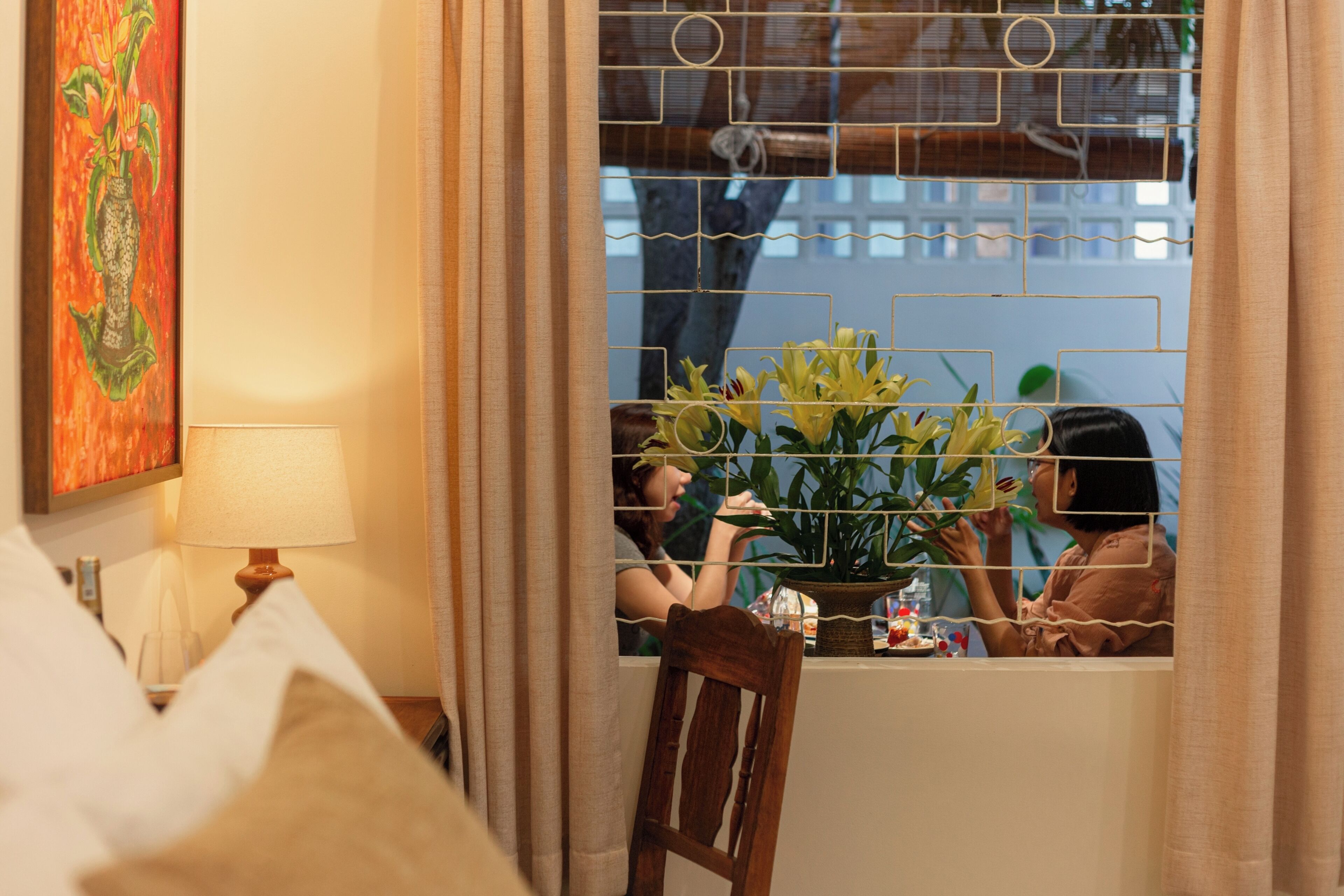 Une pièce avec une fenêtre, une lampe, une chaise et une table sur laquelle se trouve une plante.