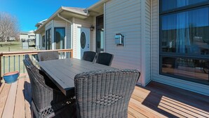 A deck with a table and chairs, a window, and a door.