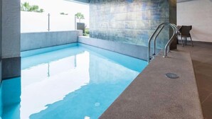 Una piscina con barandilla metálica y pared de azulejos.