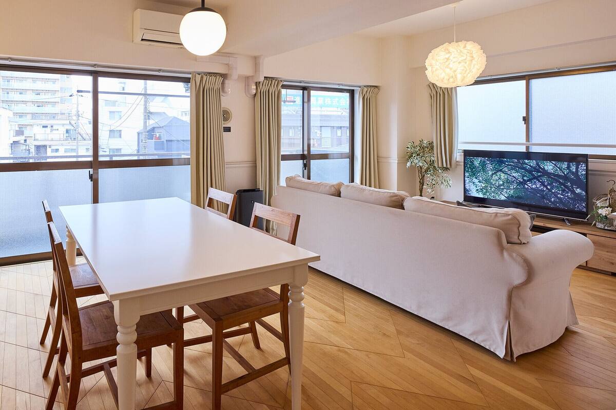 A modern living room with a dining table, sofa, and TV.