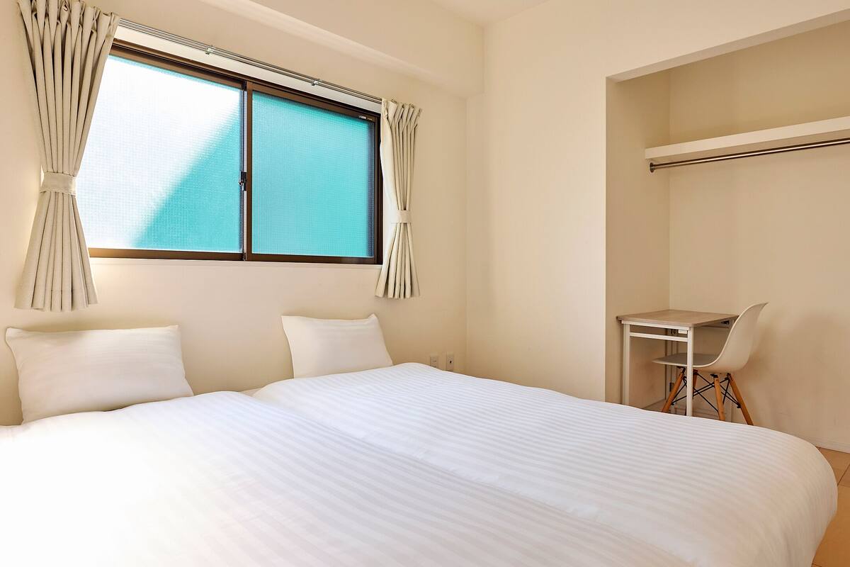 A bedroom with a bed, a desk, and a chair.