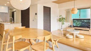 Une cuisine moderne avec une table à manger ronde, des chaises en bois, un four encastré et une grande fenêtre avec des rideaux.