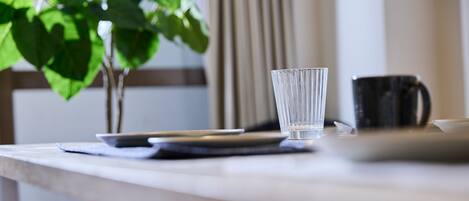 A table with a glass, a black mug, and a plant.
