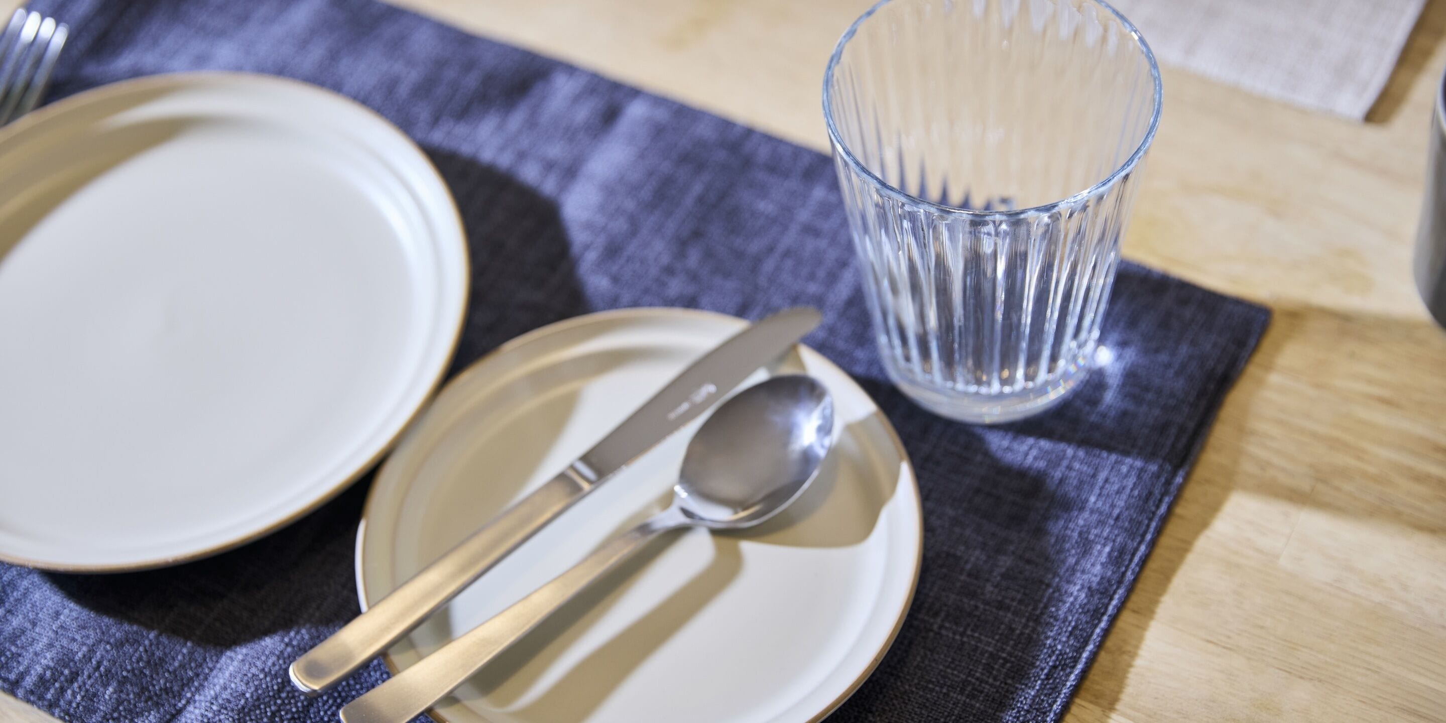 A table set with a plate, a knife, a spoon, and a glass.