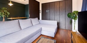 A modern living room with a sectional sofa, a wooden coffee table, a TV, and a potted plant.