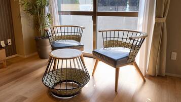 A room with two wicker chairs, a small round table, and a potted plant.