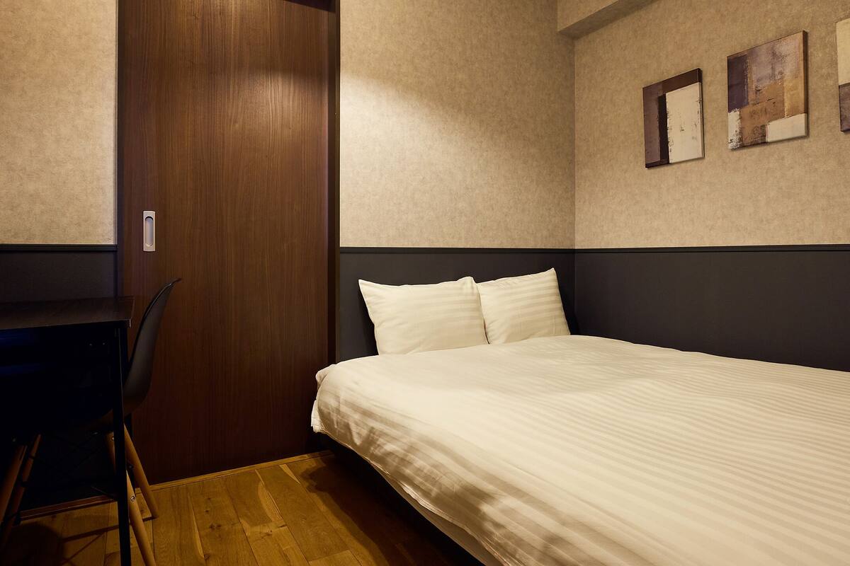 A bedroom with a bed, a desk, and a chair.