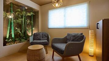 A room with a large window, a chair, a small table, and a tall lamp.