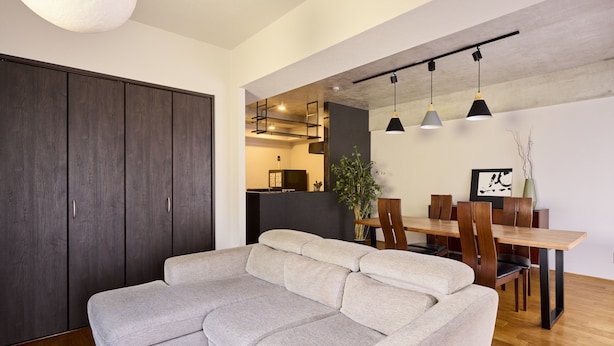 Un salon moderne comprenant un canapé, une table à manger, des chaises, des luminaires suspendus et une grande armoire.