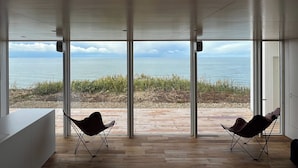 A modern interior with large windows, two folding chairs, and a wooden floor.