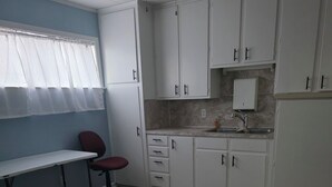 A kitchen with white cabinets, a countertop, a sink, and a ceiling fan.