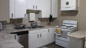 A kitchen with white cabinets, a dishwasher, a stove, and a microwave.