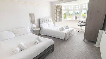 A hotel room with two beds, a desk, a chair, a wardrobe, and a window with curtains.